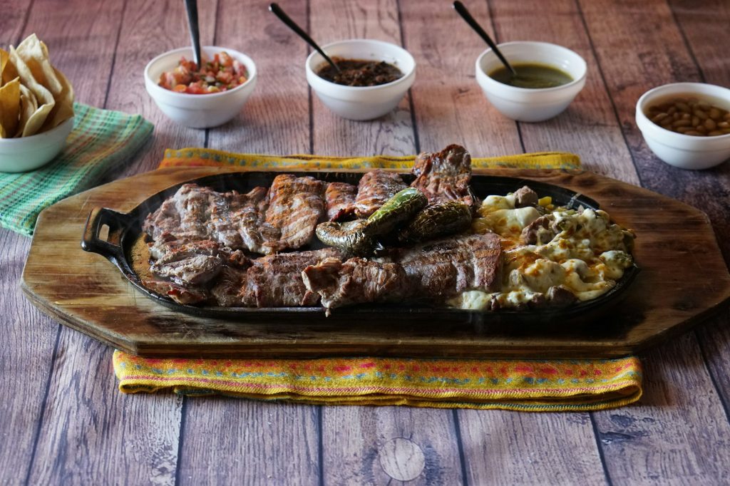 Closeup shot of delicious parrillada, different kind of meats on one plate on a wooden surface